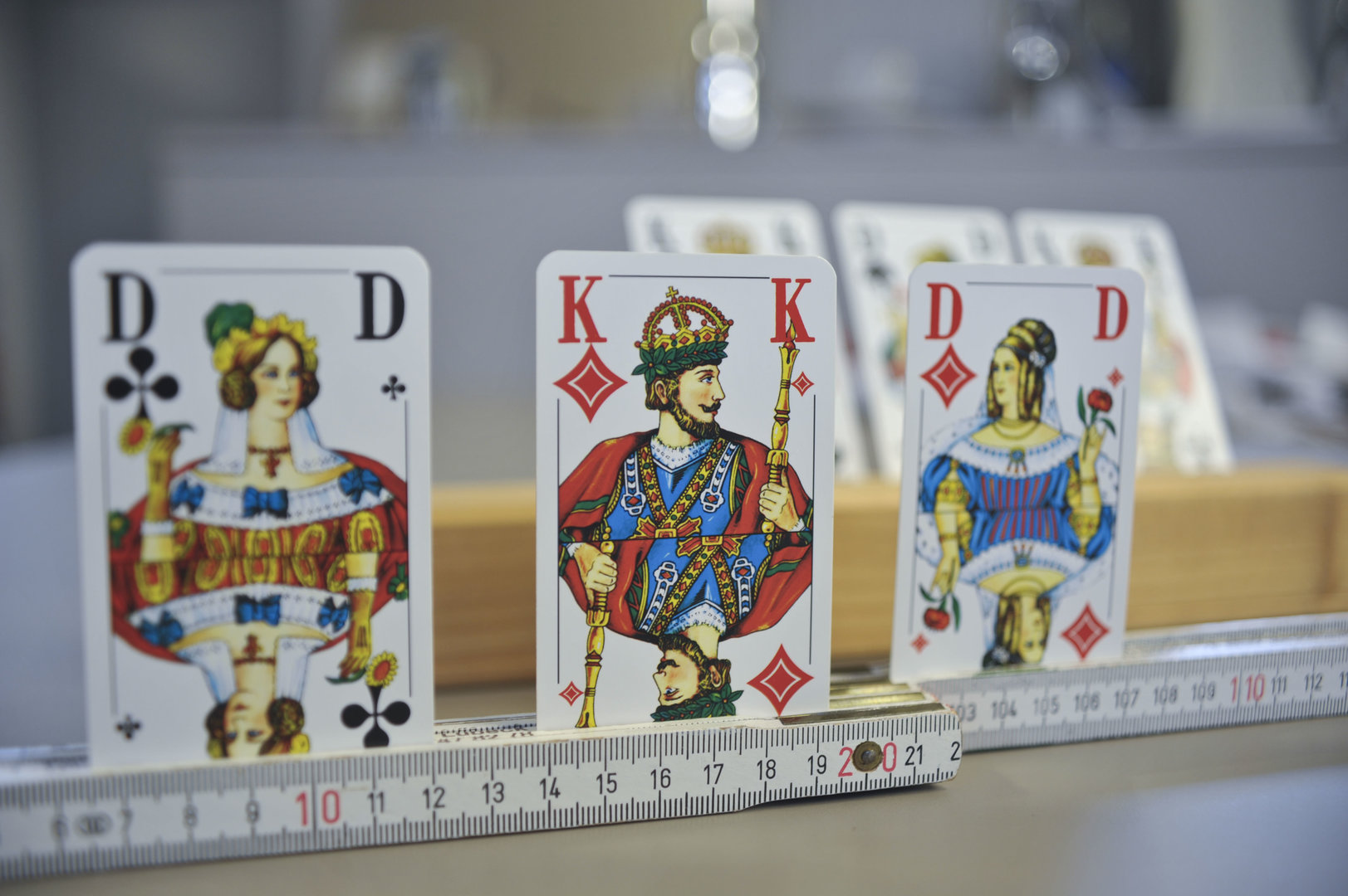Idee für einfache Alltagshilfen: Karten werden beim Spielen in einen liegenden Zollstock gesteckt, um sie zu halten.