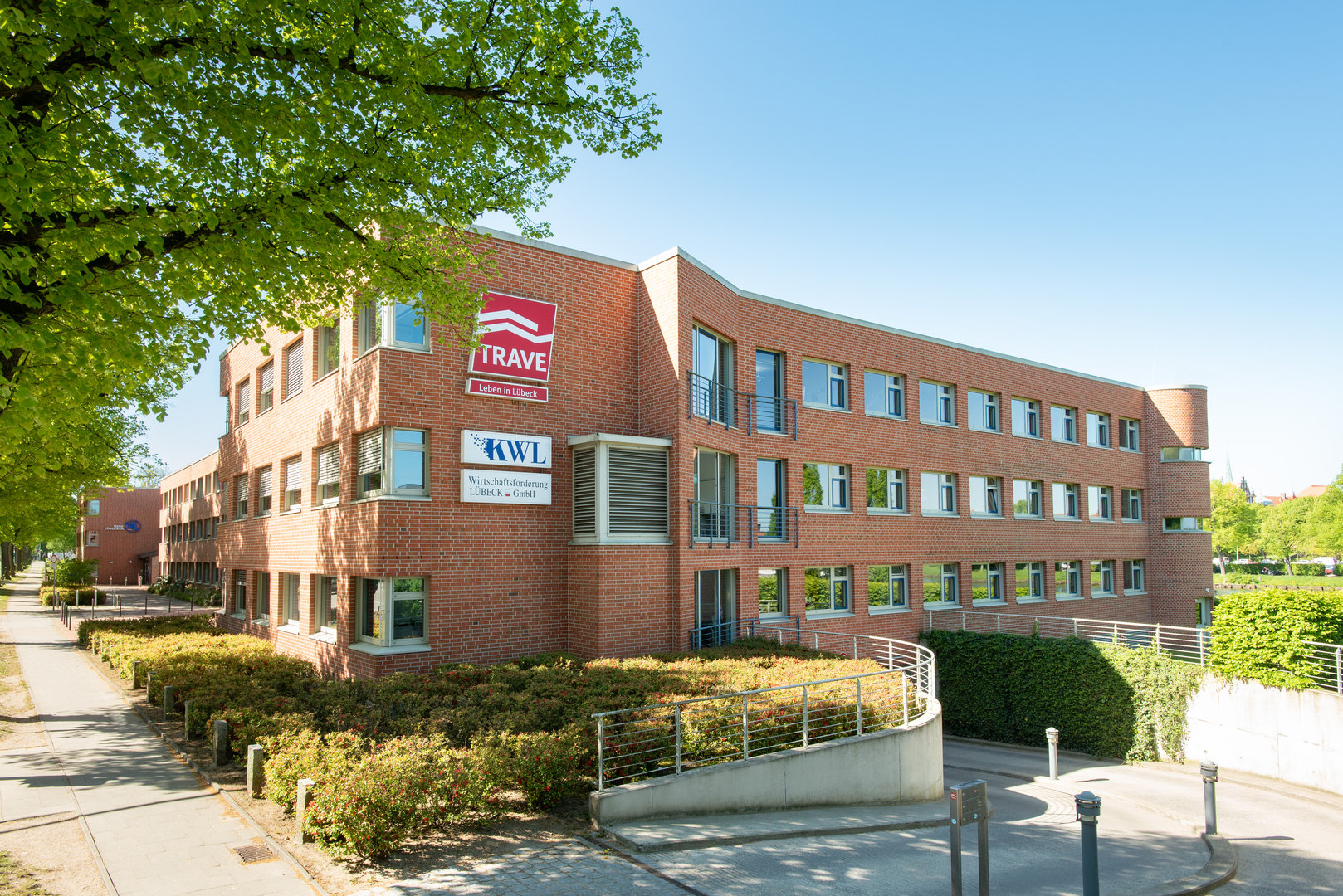 Das Gebäude der TRAVE-Geschäftsstelle in der Falkenstraße 11. Man sieht eine Fensterfront mit dem TRAVE-Logo und die Einfahrt zur Tiefgarage. Das Gebäude der TRAVE-Geschäftsstelle in der Falkenstraße 11. Man sieht eine Fensterfront mit dem TRAVE-Logo und die Einfahrt zur Tiefgarage.