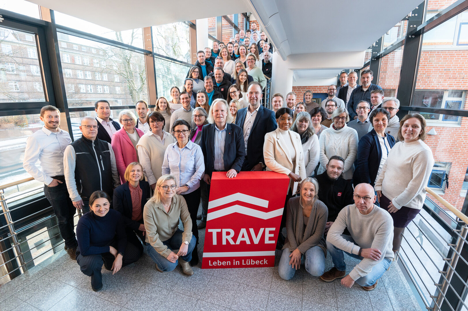 Das TRAVE-Team im Treppenhaus der Falkenstraße 11. Im Vordergrund das TRAVE-Logo und die Geschäftsführer Dr. Matthias Rasch und Sebastian Weist.