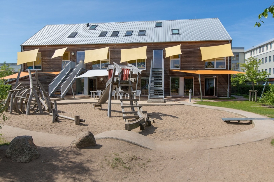 Eine Kindertagesstätte mit Sonnensegeln und schönem Spielplatz.
